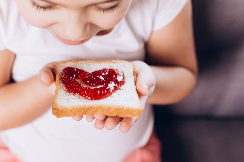 kid with fresh bread and strawberry marmalade