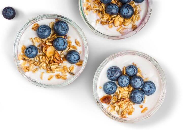 3 glasses of yogurts with cereal and fruit on it