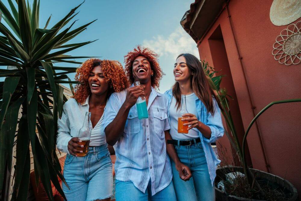 three people laughing while one enjoys a soda enhanced with IFF FLAVORFIT™ taste modulation