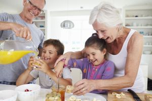 Grandparents helping grandkids with breakfast, including orange juice, fruit, cereal, bread products and more