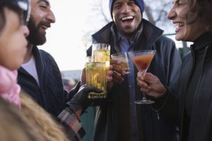Group of friends outside during Dry January, talking and holding a variety of different no-alcohol and low-alcohol beverages