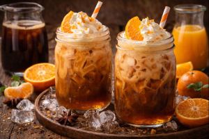 Top flavor trend: mandarin-flavored iced coffee in jars with whipped cream, orange slices, straws and oranges and orange juice surrounding the jars