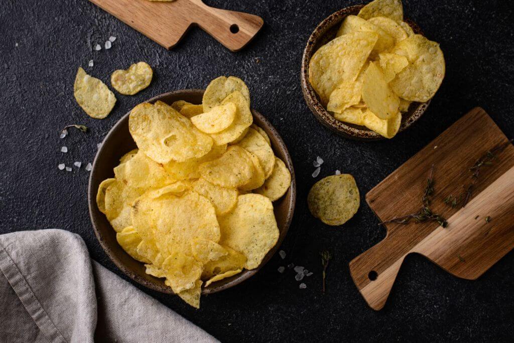 Salted potato chips in bowls and scattered on a table