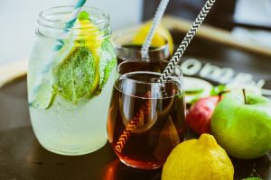 A range of different kombucha and health beverages in glasses and sitting next to citrus fruits on a table.