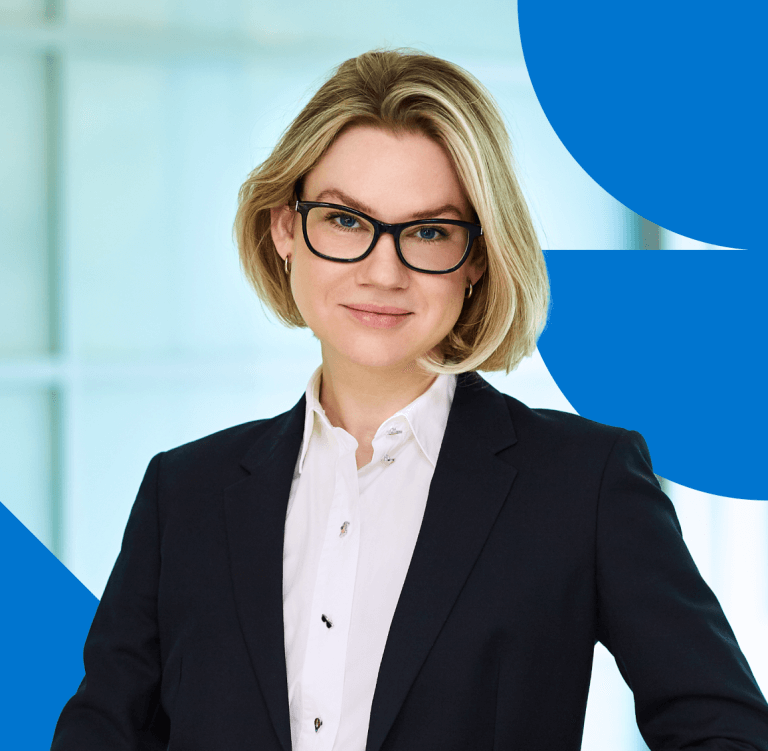 A woman in a business suit with short blonde hair and glasses